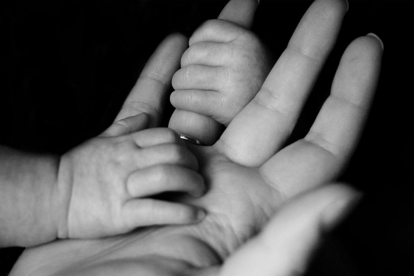 Babyhand greift nach der Hand der Mama.