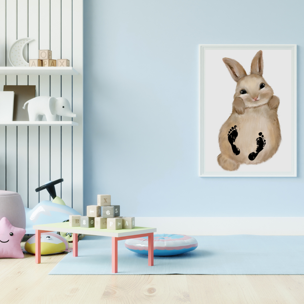 Personalisiertes Bild vom Hasen mit Baby-Fußabdrücken hängt im weißen Bilderrahmen im Kinderzimmer auf.