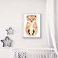 Geschenk zur Geburt mit Löwen-Motiv hängt gerahmt an der Wand über dem Babybett mit einer Kuscheldecke darin.